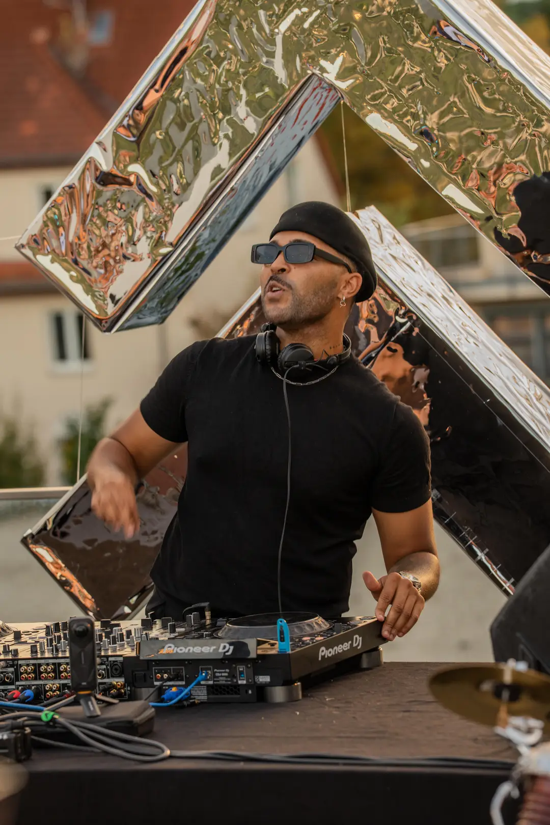 SEKOU mixing on the rooftop in a black tee and beret
