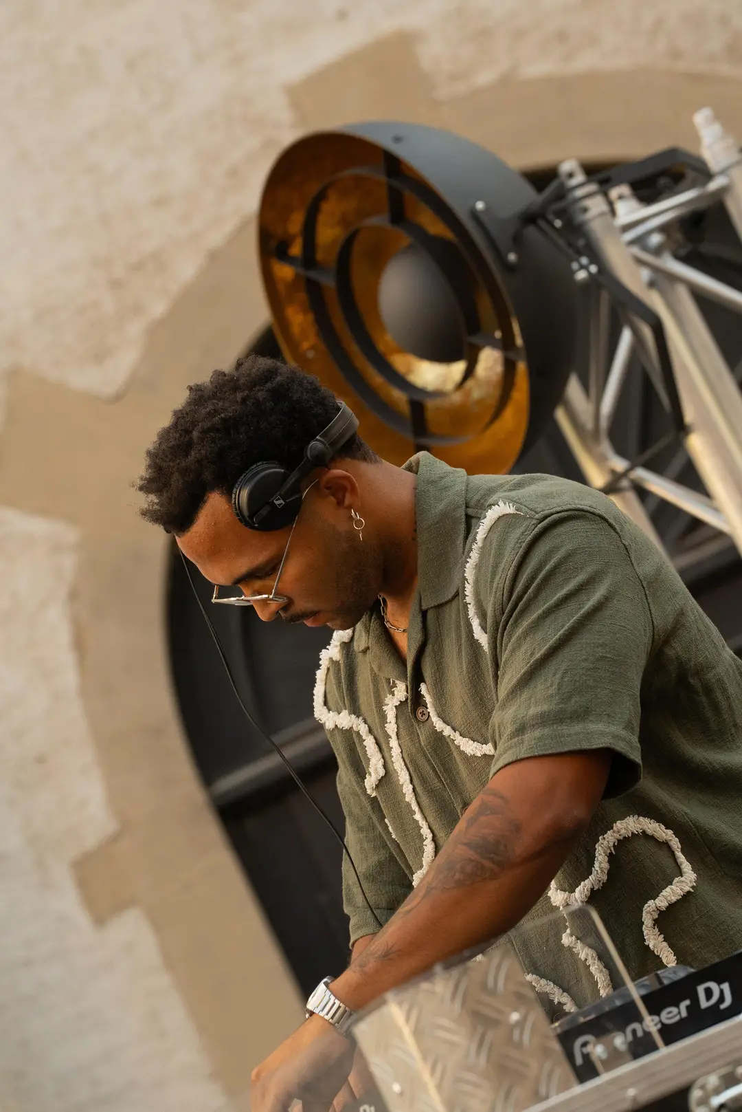 SEKOU in profile at the decks, a gold horn speaker behind him