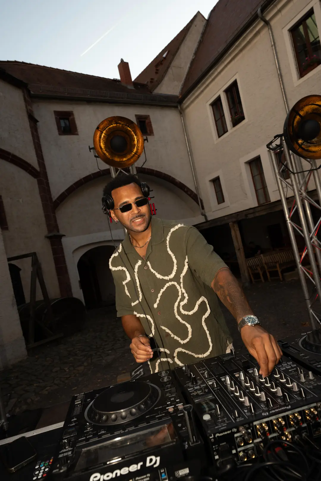 SEKOU in the castle courtyard between two gold horn speakers