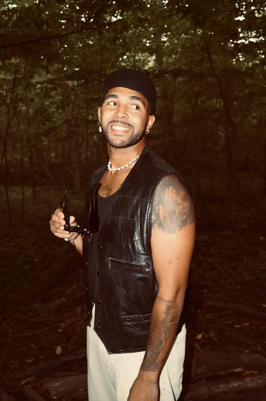 SEKOU laughing in a dark forest, glasses in hand